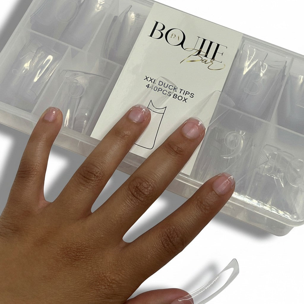 Daboujiebar XXL clear duck nail tips in a divided case. A hand with natural nails is shown next to the case.